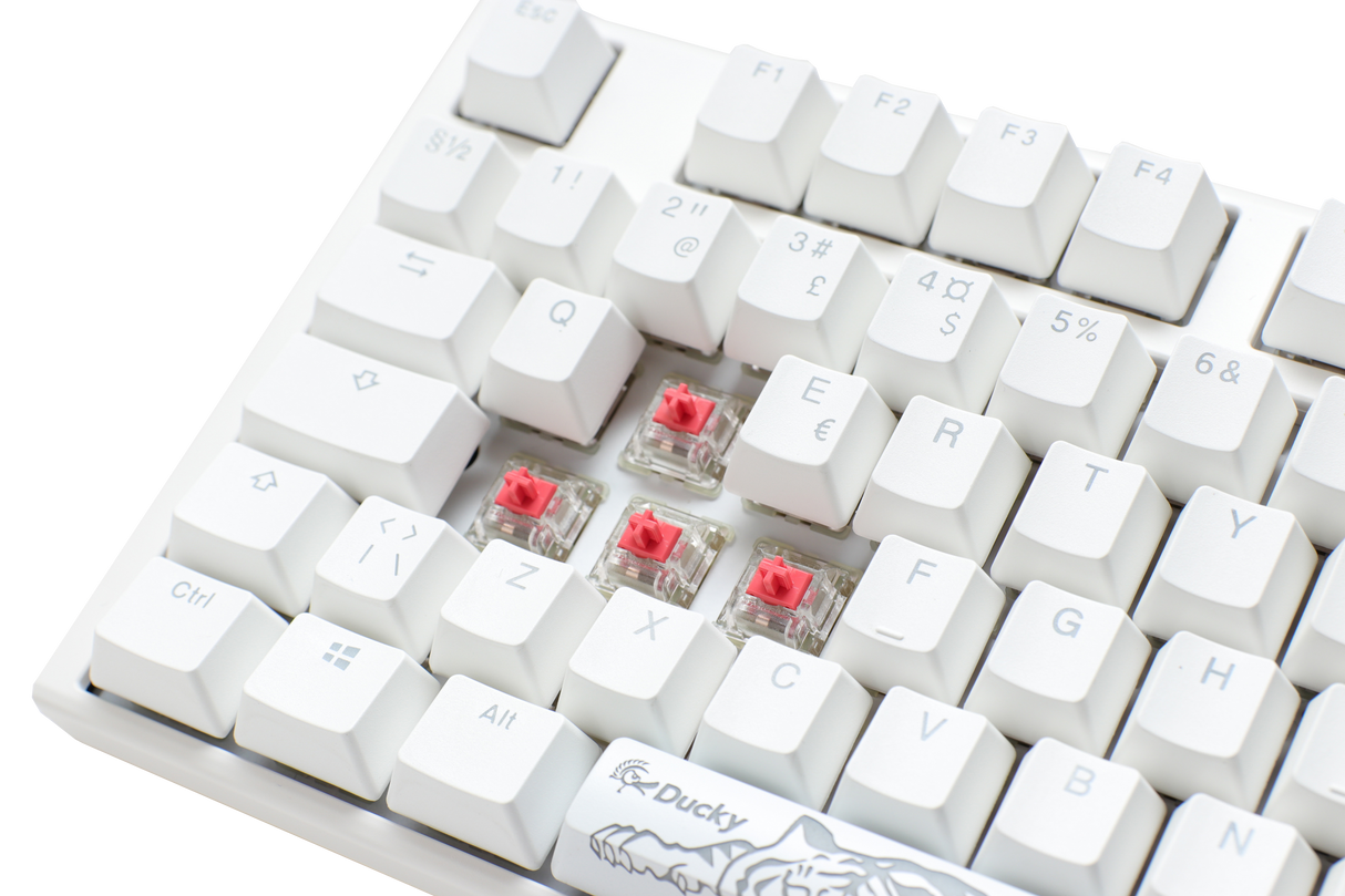 Close-up of a Ducky One 3 - Classic Pure White Nordic full-size mechanical keyboard with white PBT keycaps and visible Cherry Silent Red switches under the 'x,' 'c,' and 'v' keys, set against a light background.