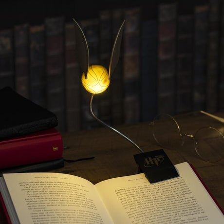 Harry Potter Golden Snitch-boglampe tændt og fastgjort til en åben bog