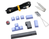 An assortment of keyboard accessories including a Ducky Cherry Silent Red USB cable, blue keycaps, a keycap puller, and a Ducky branded wrist rest, all set against a transparent background.