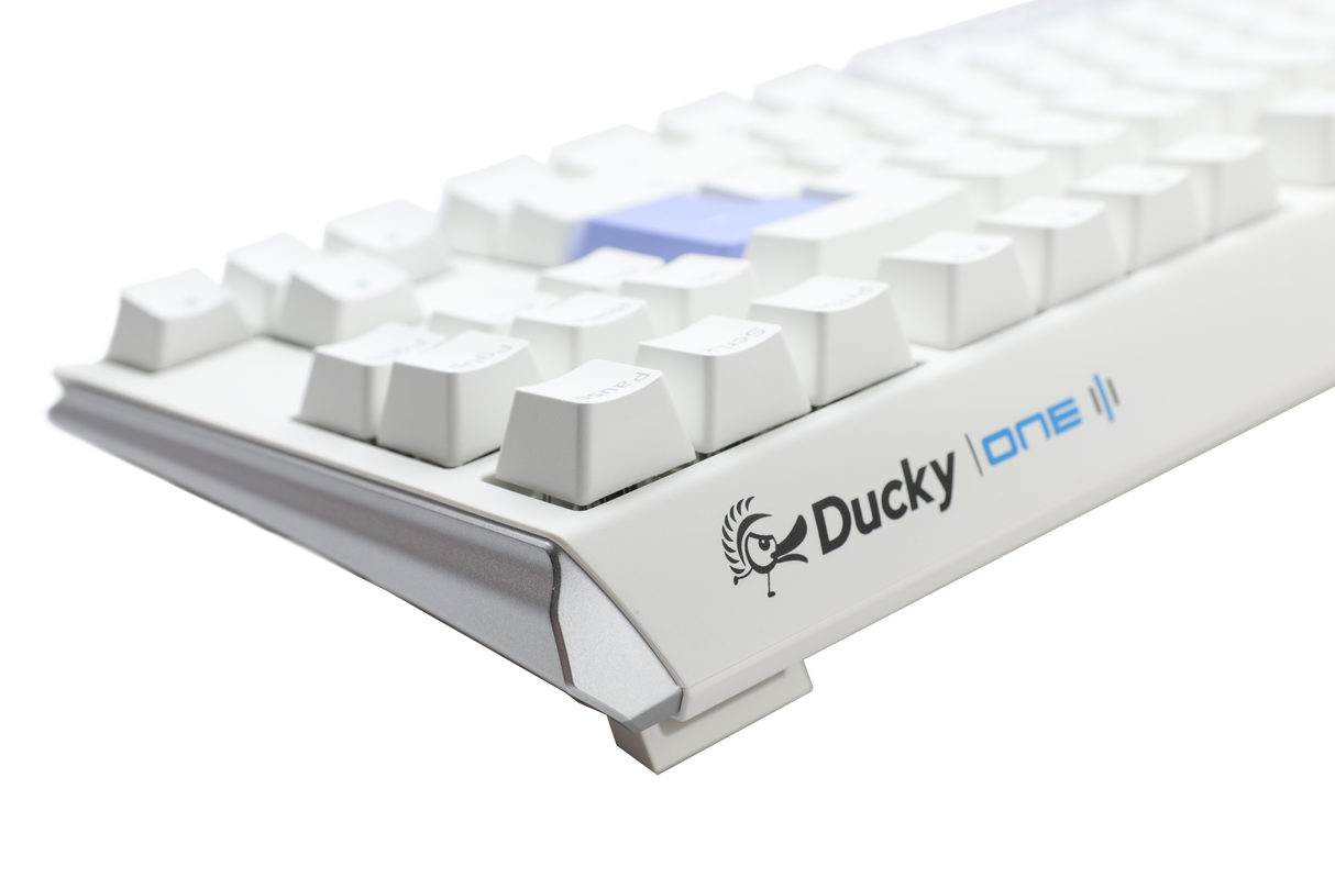 A close-up of a white mechanical keyboard, featuring PBT keycaps and the "Ducky" brand visible on the front side, set against a plain, light gray background.