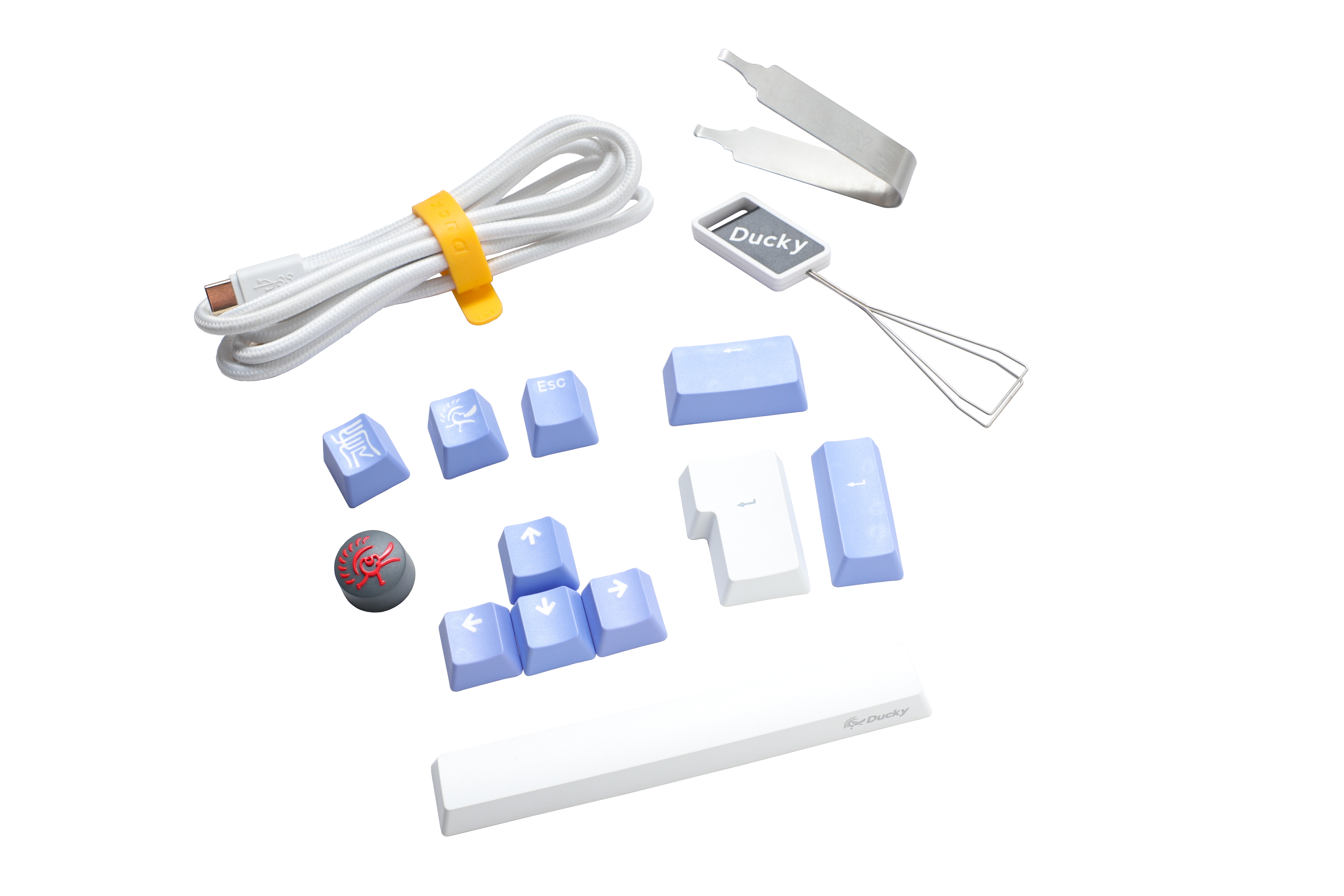 Assorted computer keyboard accessories including a white USB cable, a Ducky branded wire keycap puller, blue PBT keycaps, a red Cherry MX key switch, and silicone stabilizers.