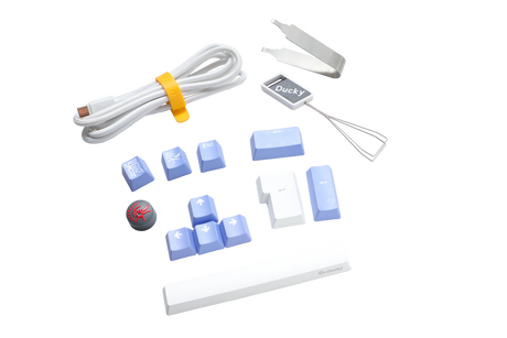 Assorted computer keyboard accessories including a white USB cable, a Ducky branded wire keycap puller, blue PBT keycaps, a red Cherry MX key switch, and silicone stabilizers.