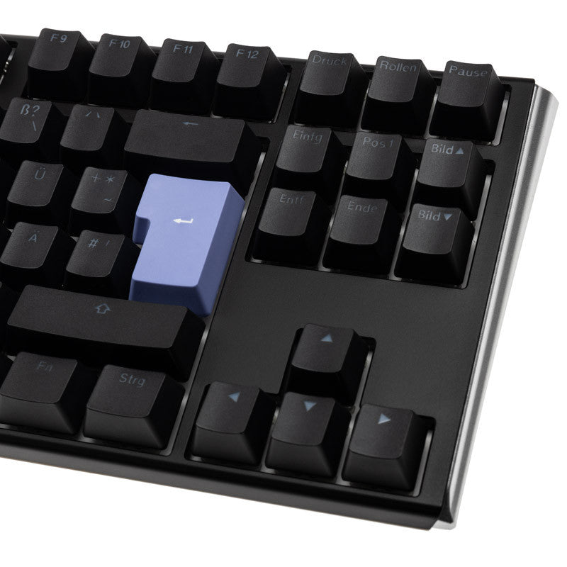 A close-up of a Ducky One 3 - Classic Black / White Nordic - TKL - Cherry Blue mechanical keyboard with black keys, featuring a distinctly colored blue enter key. The keys display white labels for function and control commands.